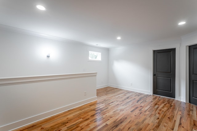 basement with light hardwood / wood-style floors and ornamental molding