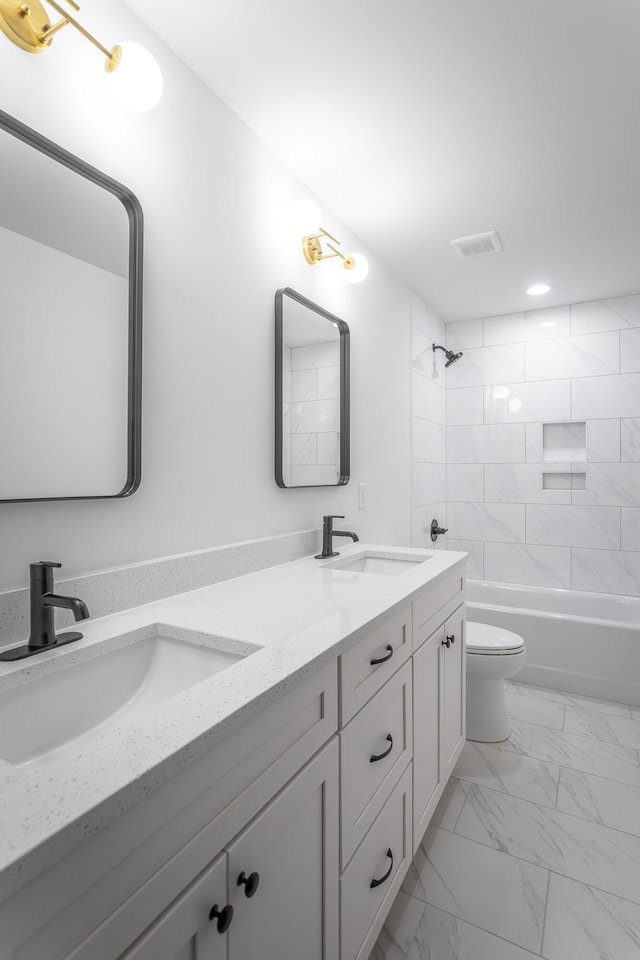 full bathroom with vanity, tiled shower / bath combo, and toilet