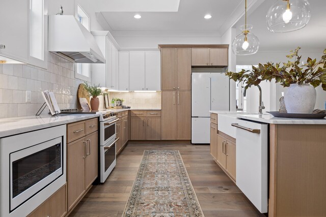 kitchen featuring dark hardwood / wood-style floors, wall chimney range hood, stainless steel appliances, and hanging light fixtures