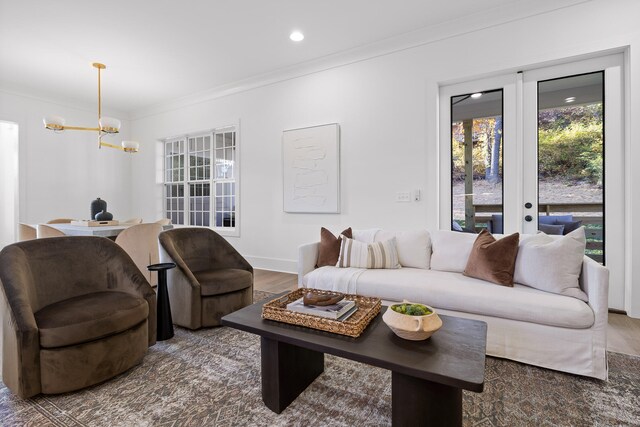 living room with an inviting chandelier, crown molding, dark wood-type flooring, and french doors