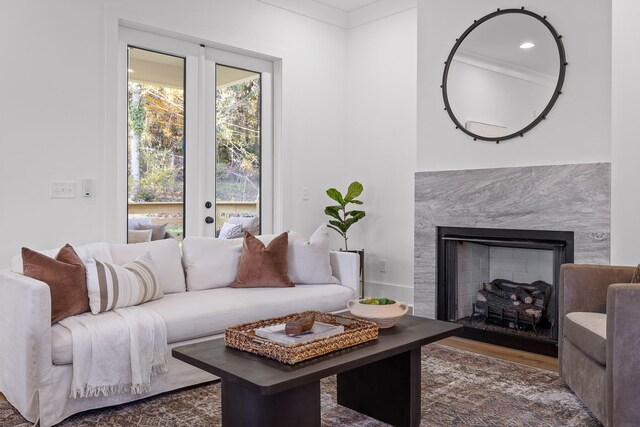 living room featuring hardwood / wood-style floors, ornamental molding, and a high end fireplace