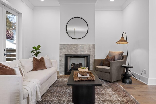 living room with a premium fireplace, dark wood-type flooring, and ornamental molding