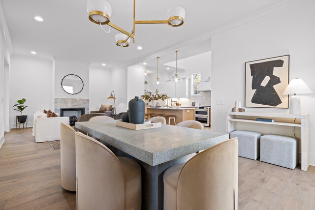 interior space featuring a fireplace, light hardwood / wood-style floors, crown molding, and a notable chandelier