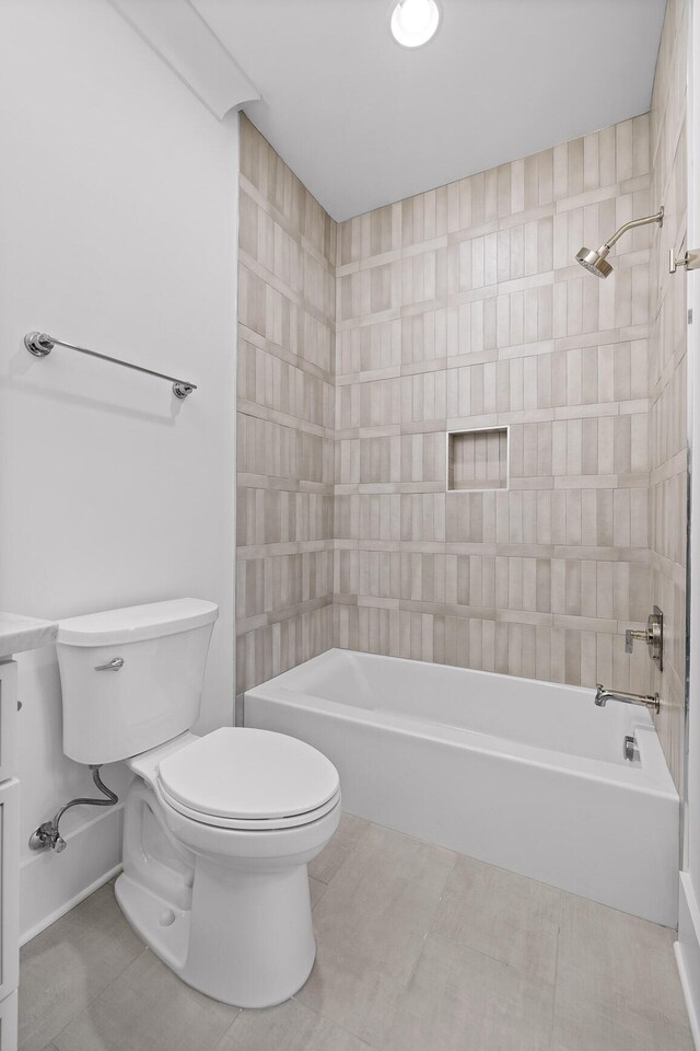 bathroom featuring tile patterned flooring, tiled shower / bath combo, and toilet