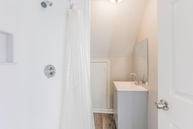 bathroom with wood-type flooring, vanity, vaulted ceiling, and walk in shower