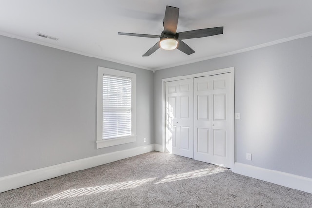 unfurnished bedroom featuring ceiling fan, a closet, carpet, and crown molding