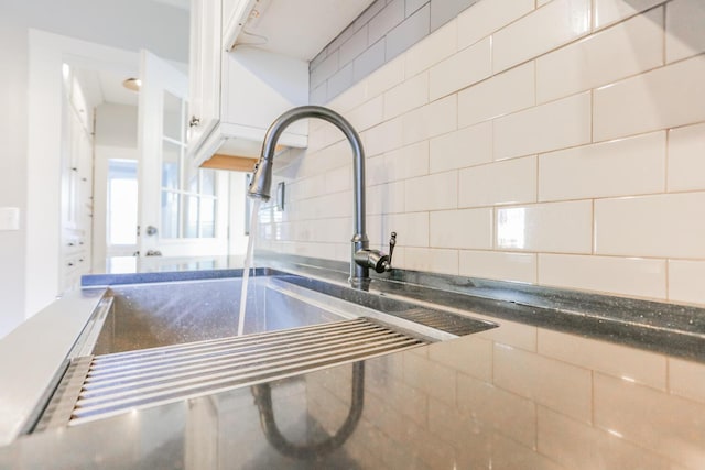 interior details featuring white cabinets, sink, and backsplash