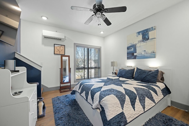 bedroom with wood-type flooring, a wall mounted AC, and ceiling fan