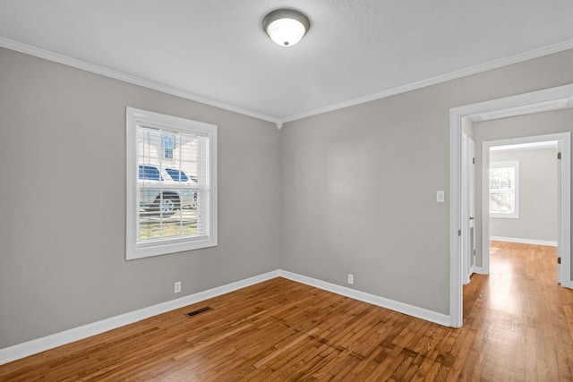 unfurnished room featuring wood-type flooring, ornamental molding, and a healthy amount of sunlight