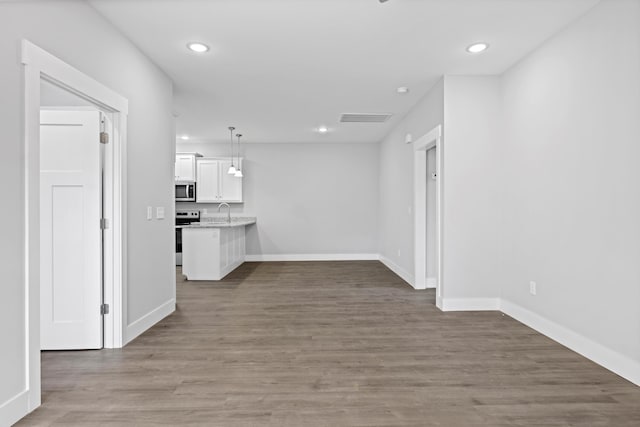 interior space with visible vents, white cabinetry, appliances with stainless steel finishes, dark wood-style floors, and pendant lighting