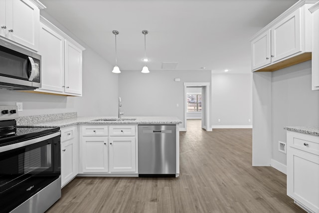 kitchen featuring pendant lighting, stainless steel appliances, a sink, and white cabinets