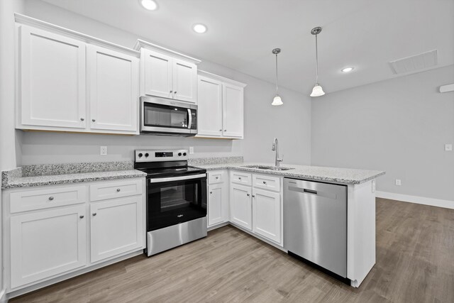 kitchen featuring stainless steel appliances, hanging light fixtures, a sink, and white cabinets