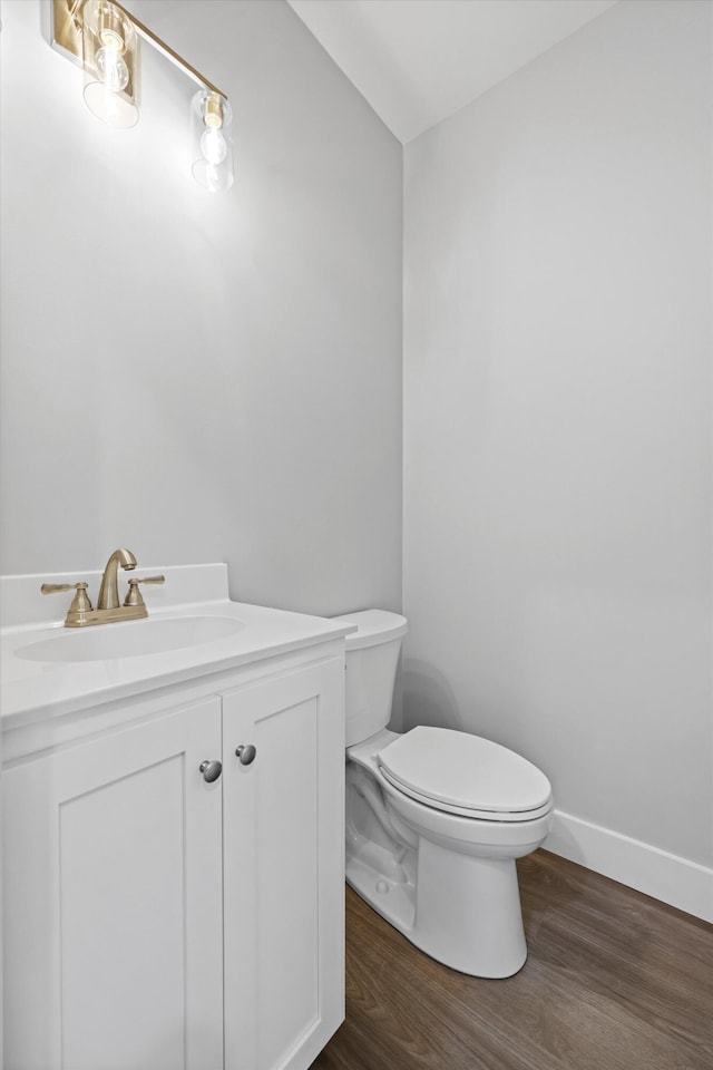 bathroom featuring toilet, wood finished floors, vanity, and baseboards