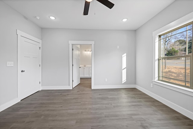 unfurnished bedroom featuring dark wood-style flooring, recessed lighting, ensuite bath, and baseboards