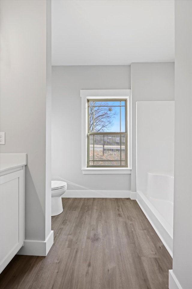 bathroom with toilet, baseboards, wood finished floors, and vanity