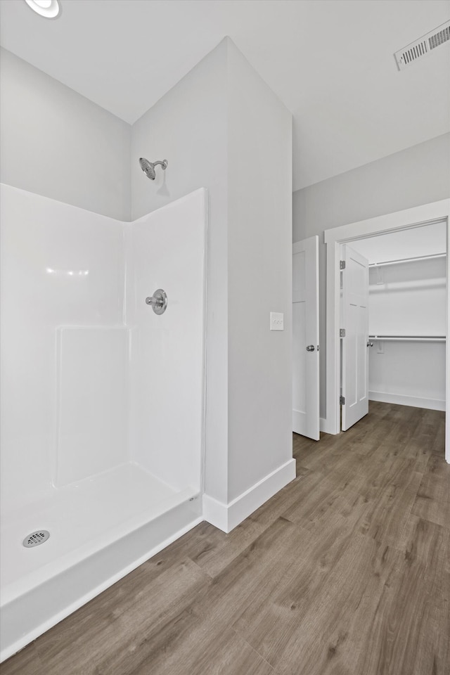 bathroom featuring wood finished floors, walk in shower, a walk in closet, and visible vents