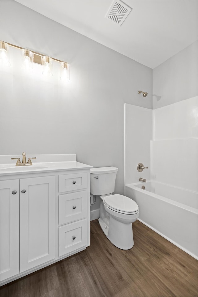 bathroom featuring visible vents, toilet, wood finished floors, bathtub / shower combination, and vanity