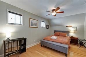 bedroom with ceiling fan, light hardwood / wood-style flooring, and vaulted ceiling