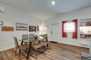 dining area featuring a wall mounted air conditioner and wood-type flooring