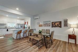 dining area with an AC wall unit and light hardwood / wood-style flooring