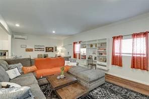 living room with wood-type flooring and a wall unit AC