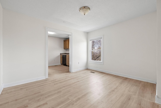 empty room featuring light wood-type flooring and a textured ceiling