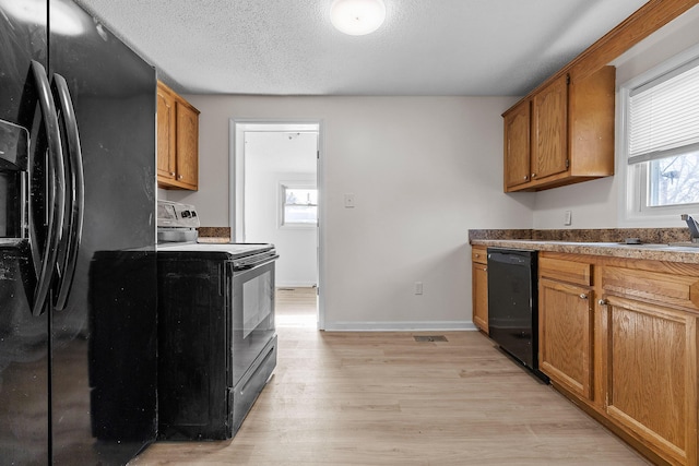 kitchen featuring sink, a textured ceiling, light hardwood / wood-style flooring, and black appliances