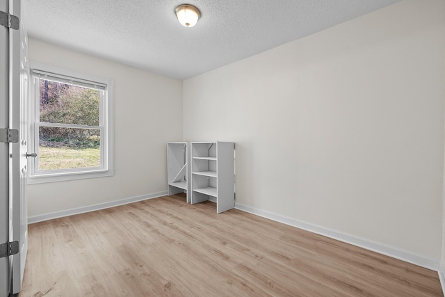 unfurnished room with light hardwood / wood-style flooring and a textured ceiling