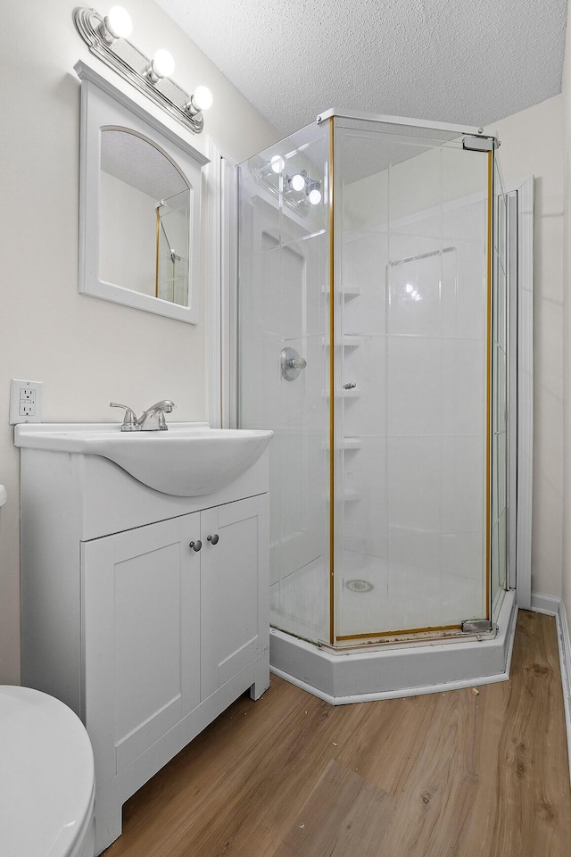 bathroom featuring vanity, wood-type flooring, a textured ceiling, and a shower with shower door