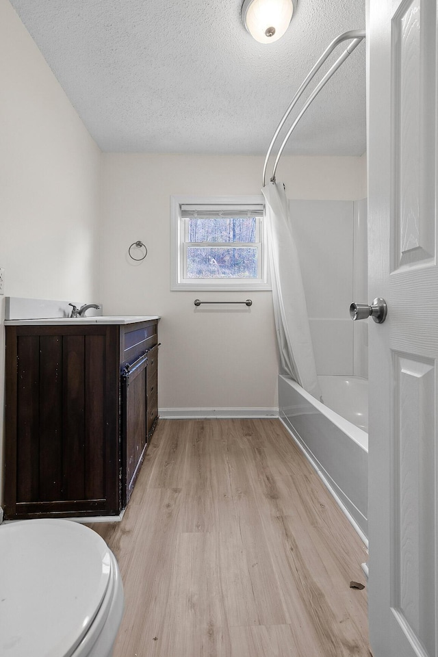 full bathroom featuring hardwood / wood-style floors, a textured ceiling, toilet, vanity, and shower / tub combo