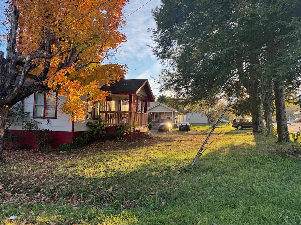 view of side of home featuring a yard and covered porch