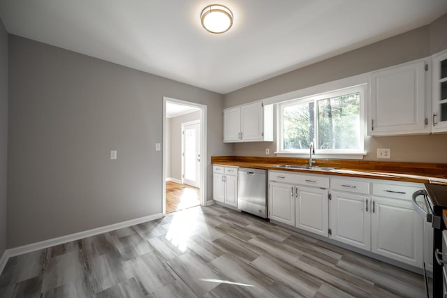 kitchen with appliances with stainless steel finishes, light wood-type flooring, sink, butcher block countertops, and white cabinetry