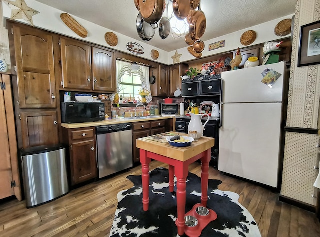 kitchen with sink, stainless steel dishwasher, white refrigerator, a textured ceiling, and hardwood / wood-style flooring