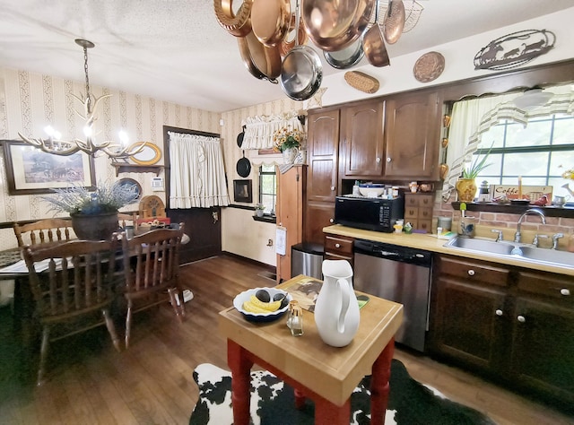 kitchen with stainless steel dishwasher, dark wood-type flooring, sink, pendant lighting, and an inviting chandelier