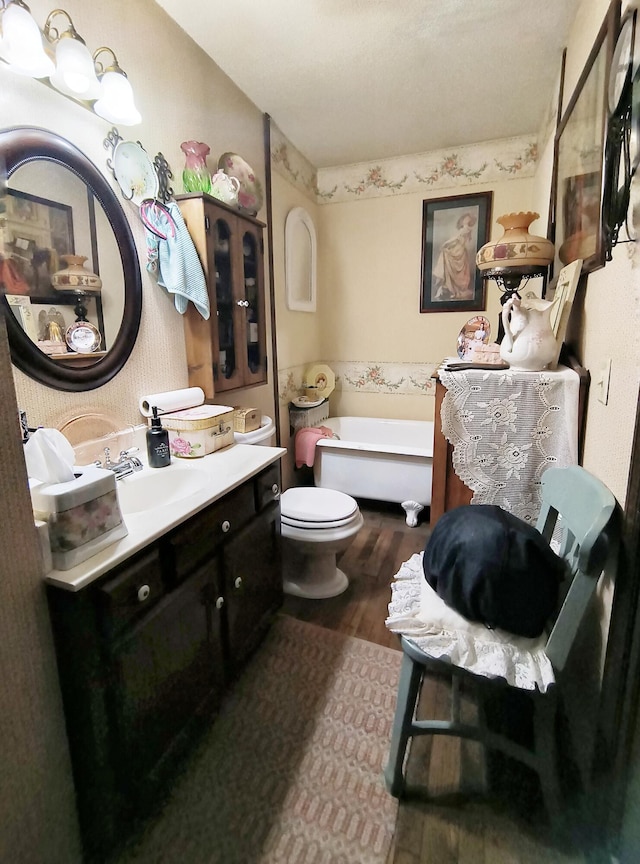 bathroom with hardwood / wood-style flooring, vanity, toilet, and a bath