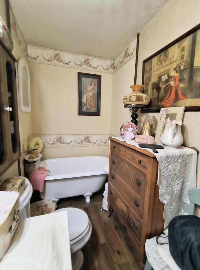 bathroom with a washtub, wood-type flooring, and toilet