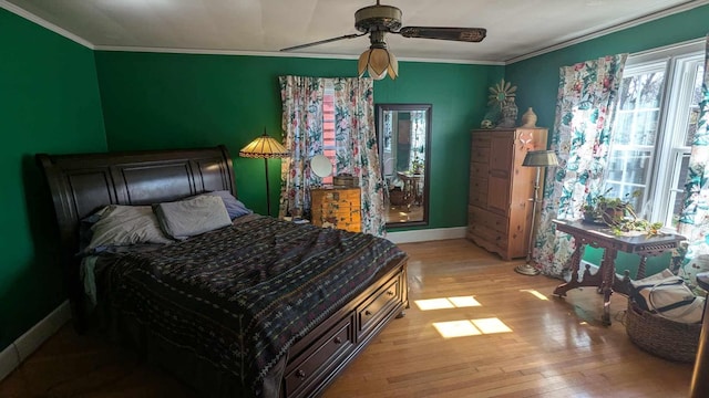 bedroom with light wood finished floors, a ceiling fan, baseboards, and ornamental molding