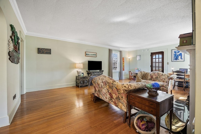 living room featuring baseboards, wood-type flooring, a textured ceiling, and ornamental molding