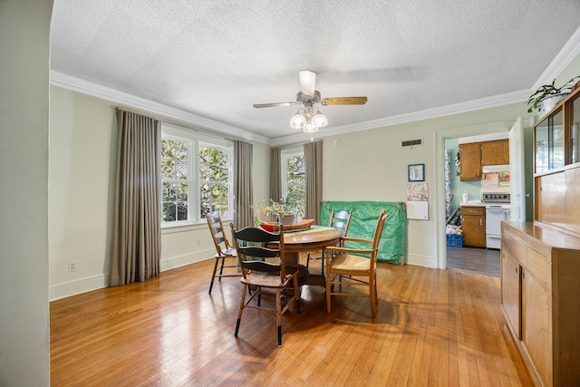 dining space with light wood-style flooring, ornamental molding, and ceiling fan