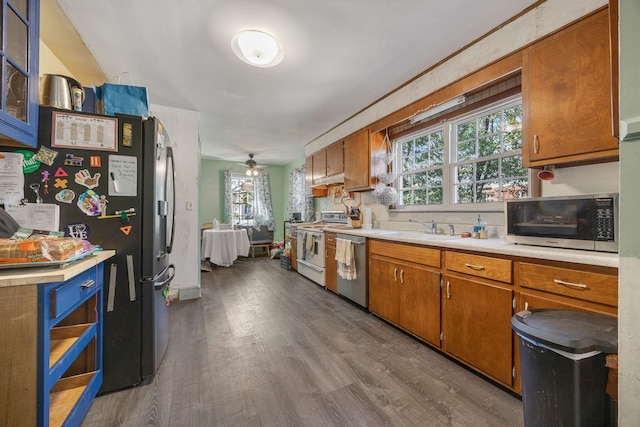 kitchen featuring light countertops, wood finished floors, brown cabinetry, stainless steel appliances, and a sink