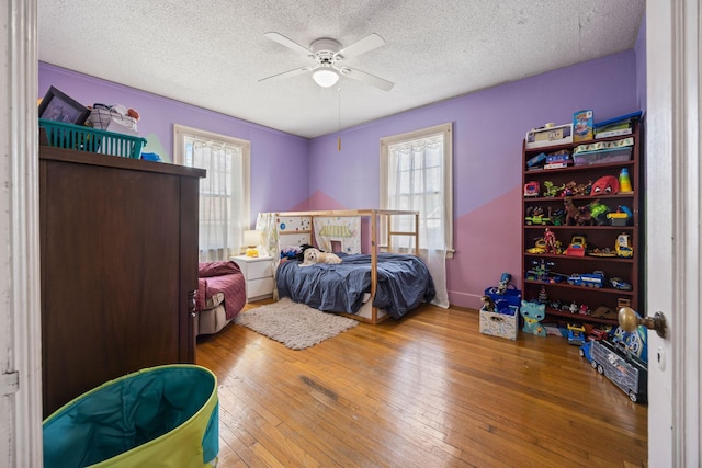 bedroom with a textured ceiling, a ceiling fan, and hardwood / wood-style floors