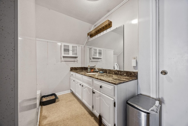 bathroom with a textured ceiling, vanity, and vaulted ceiling