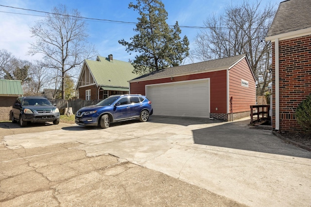 garage with concrete driveway and fence