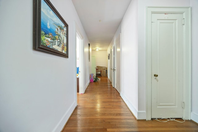 hall with baseboards and wood finished floors