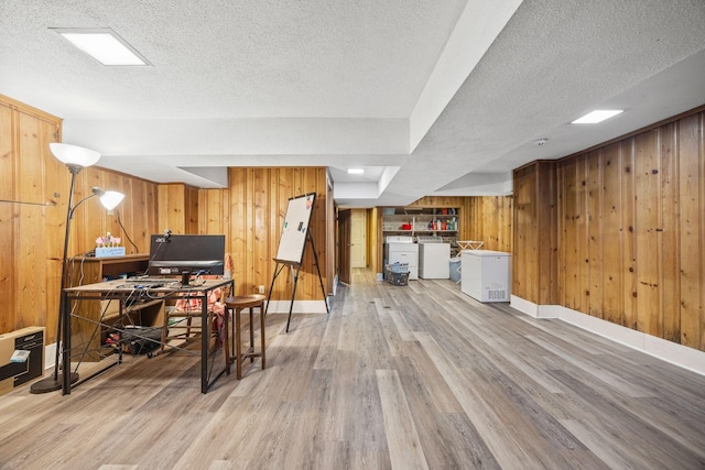 office featuring a textured ceiling, separate washer and dryer, wood walls, light wood finished floors, and baseboards