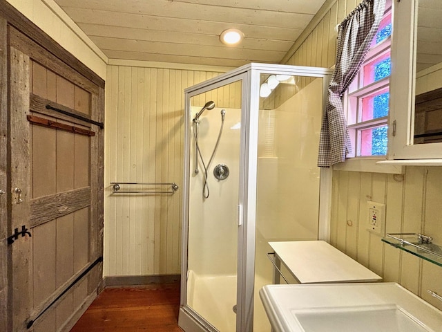 bathroom featuring wood walls, sink, wood-type flooring, and a shower with shower door