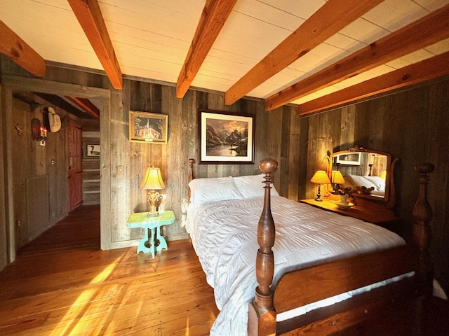 bedroom with beamed ceiling, hardwood / wood-style floors, and wooden walls