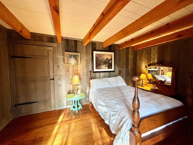 bedroom with beam ceiling, wood walls, and wood-type flooring