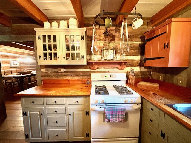 kitchen featuring wooden walls, white gas stove, decorative light fixtures, and wooden counters