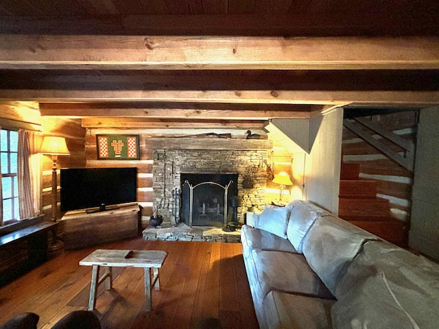 living room featuring beamed ceiling, a stone fireplace, and hardwood / wood-style floors